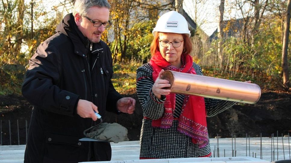 Landrat Bernd Lütjen und Schulleiterin der IGS, Karina Kögel-Renken, setzen traditionell eine Zeitkapsel in den Grundstein ein. Der Bau des Oberstufenhauses wird voraussichtlich zu den Herbstferien 2019 fertiggestellt sein.  Foto: mr