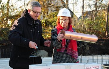 Landrat Bernd Lütjen und Schulleiterin der IGS, Karina Kögel-Renken, setzen traditionell eine Zeitkapsel in den Grundstein ein. Der Bau des Oberstufenhauses wird voraussichtlich zu den Herbstferien 2019 fertiggestellt sein. Foto: mr