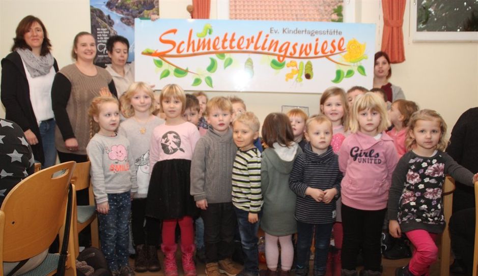 25 Kinder im Alter von drei bis sechs Jahren besuchen zurzeit die evangelische Kindertagesstätte „Schmetterlingswiese.“ Stolz zeigen sie ihr neues Hausschild, das vor dem Eingang der Kita angebracht wird. Foto: im