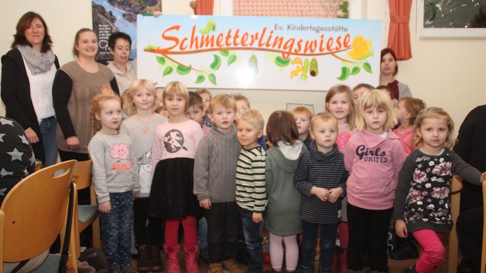 25 Kinder im Alter von drei bis sechs Jahren besuchen zurzeit die evangelische Kindertagesstätte „Schmetterlingswiese.“ Stolz zeigen sie ihr neues Hausschild, das vor dem Eingang der Kita angebracht wird. Foto: im