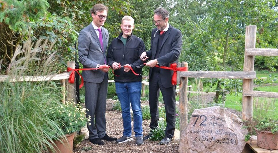 Bürgermeister Kristian Tangermann, der erste Vorsitzende der Landjugend, Malte Rohdenburg, und Pastor Wildrik Piper (von links) machten den Weg in den Park frei.  Foto: ui