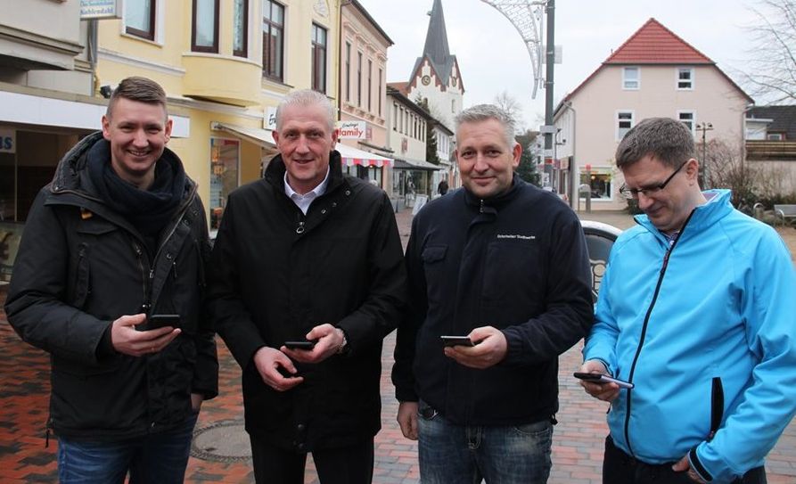 Die Antenne als kleiner weißer Kasten oben an der Straßenlampe fällt kaum auf, dafür ist die Freude von Bastian Grimm (Wirtschaftstreff), Christian Meyer-Hammerström, Sven Tienken und René Niesel (alle Osterholzer Stadtwerke) nicht zu übersehen.  Foto: eb