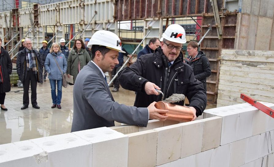Traditionell setzten Landrat Bernd Lütjen und Schulleiter Dr. Denis Ugurcu eine Zeitkapsel in das Mauerwerk ein. Foto: eb