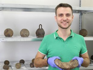 Historiker Andreas Schley mit einem Bruchstück einer hohlen Bombe. Hinter ihm sind Kanonenkugeln aus den Sammlungen des Bachmann-Museums zu sehen, die derzeit erforscht werden.
 Foto: Bachmann-Museum