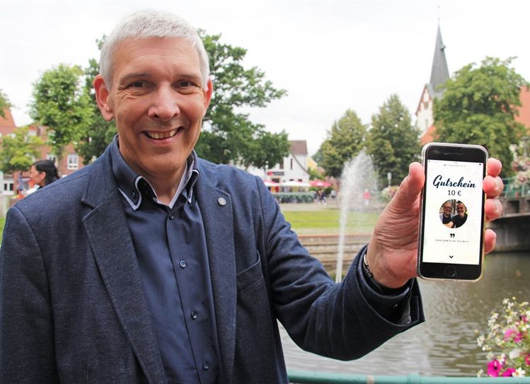 Bürgermeister Torsten Rohde macht es vor: Den Stadtgutschein kann man ganz einfach per Handy verschicken. Ab Montag gibt es sogar bis zu 20 Euro obendrauf.  Foto: jm
