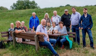 Die Mitglieder des Ortsrates Bremervörde (hinten im Halbkreis) weihen zusammen mit einer Wandergruppe die neue Bank ein.