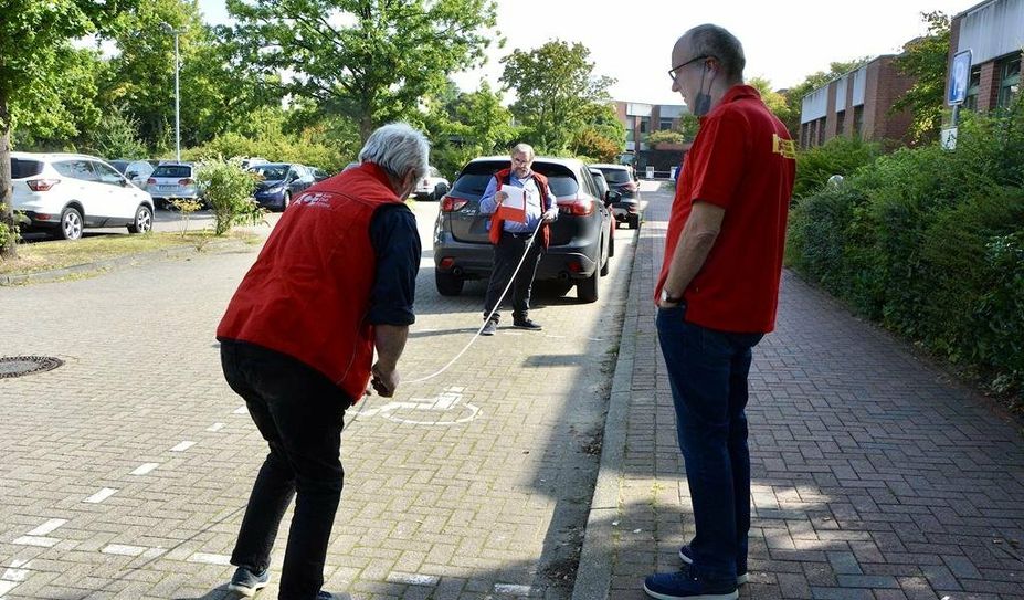 Der Bremervörder Viktor Sussek (re.) mit dem ACE-Team aus Bremerhaven auf dem Ostemed-Parkplatz in Bremervörde. Hier fehlen barrierefreie E-Lademöglichkeiten.