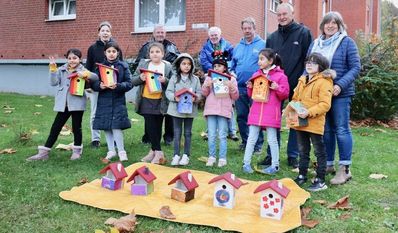 Gemeinsam mit Antje Kappel, Detlev Frank, Werner Pommer, Karl-Heinz Kabbeck, Heinz Freese und Christine Struthoff präsentieren die kleinen Baufrauen und -herren der „Rainbow Kids“ stolz die neuen „Vogeleigenheime“.