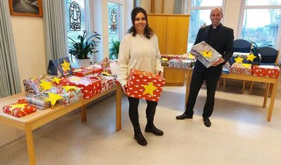 Melanie Blank und Pastor Florian von Issendorff vor den Geschenken, bevor sie unter dem Weihnachtsbaum von 51 Kindern in der Gemeinde landen.