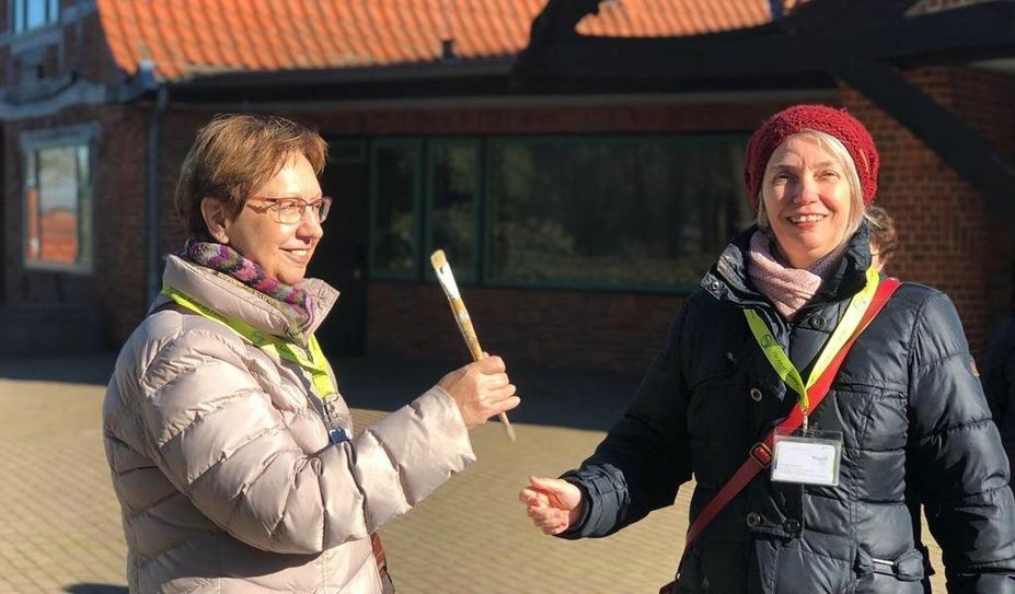 Ein Malerpinsel dient als Staffelstab.