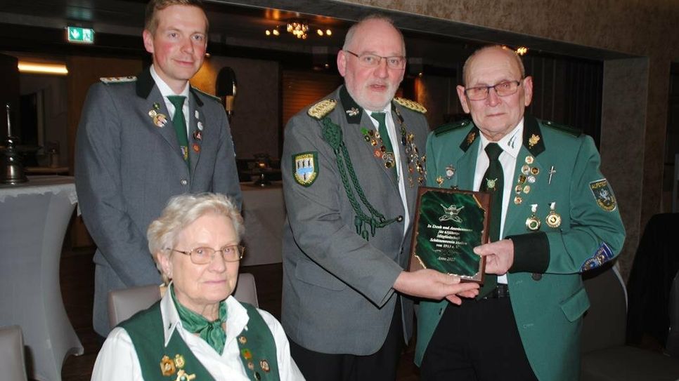 Tobias Wehber und Heino Siems überreichen dem sichtlich gerührten Reinhard Quast und seiner Frau Karin eine Plakette für 65 Jahre Mitgliedschaft im Verein.