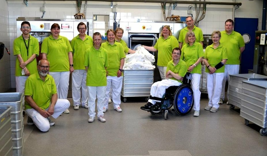 Strahlt mit der Wäsche und dem sanierten Gebäude um die Wette: Gruppenleitung Andreas 
Knikanow (links kniend) und ein Teil seines Wäscherei-Teams.