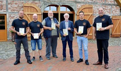 Thomas Lindner (v. li.), Jens Meyer, Gerhard Burfeindt, Hans Wilhelm Peper, Sebastian Fischer und Ortsbürgermeister Andreas Itzen präsentieren vor dem Logehuus  die druckfrischen Exemplare der Festschrift.