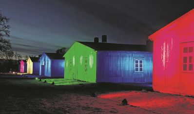 In Regenbogenfarben illuminierte Holzbaracken.