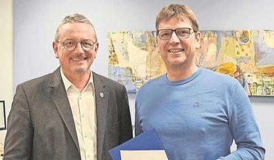 Landrat Bernd Lütjen (links) überreicht Frank Bachmann die neue Urkunde