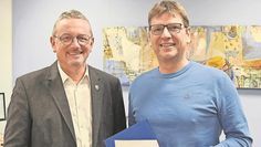 Landrat Bernd Lütjen (links) überreicht Frank Bachmann die neue Urkunde