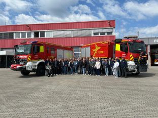 Gruppenfoto vor den großen Einsatzfahrzeugen der Werkfeuerwehr.