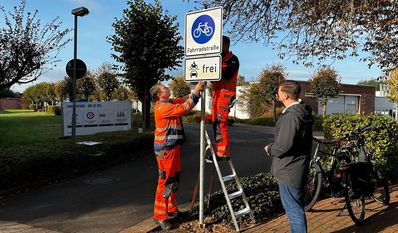 Bürgermeister Kim Fürwentsches (rechts) begutachtet das neue Schild, das von Mitarbeitenden des Baubetriebshofs aufgestellt wurde.