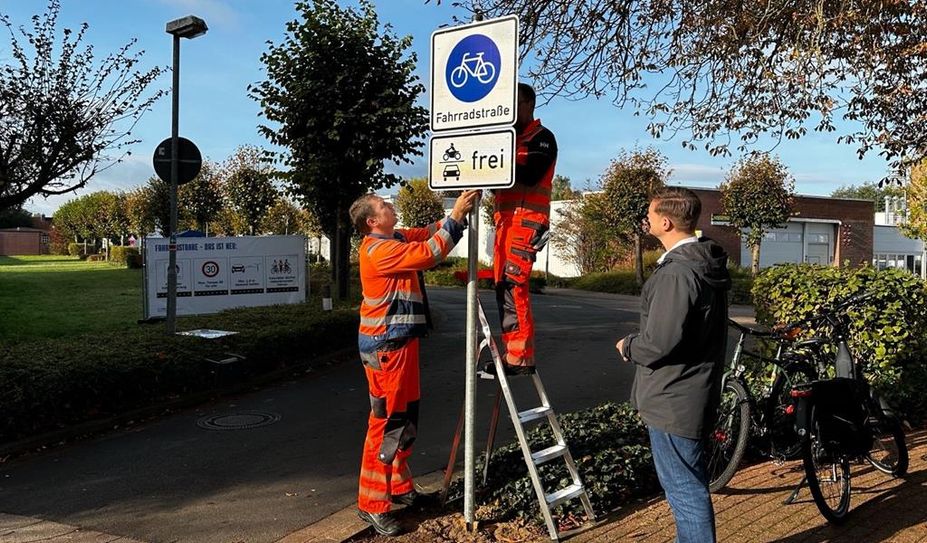Bürgermeister Kim Fürwentsches (rechts) begutachtet das neue Schild, das von Mitarbeitenden des Baubetriebshofs aufgestellt wurde.