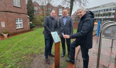 Bürgermeister Torsten Rohde (rechts) macht es vor: Einfach mit dem Smartphone den QR-Code wie hier am Schlauchturm scannen und dann der Geschichte der ehemaligen Feuerwache lauschen. Foto: cne