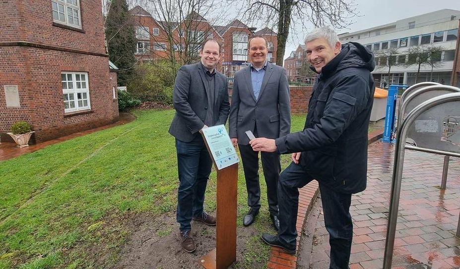 Bürgermeister Torsten Rohde (rechts) macht es vor: Einfach mit dem Smartphone den QR-Code wie hier am Schlauchturm scannen und dann der Geschichte der ehemaligen Feuerwache lauschen. Foto: cne