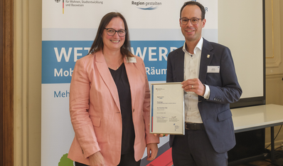 Dezernent Dominik Vinbruck übernahm die Auszeichnung von Melanie Schade, Leiterin des PG Kompetenzzentrum für Ländliche Mobilität, entgegen.