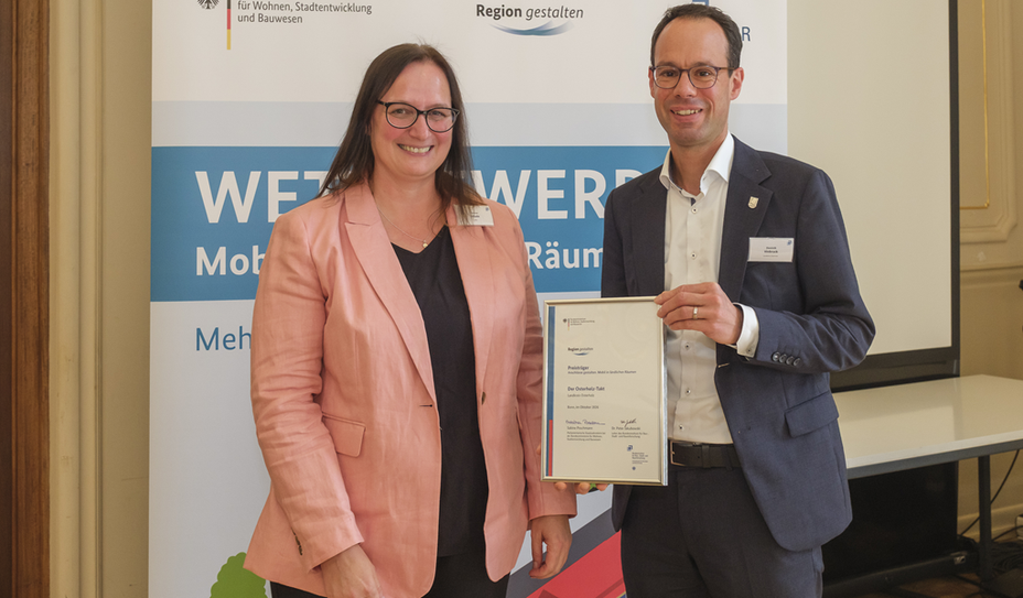 Dezernent Dominik Vinbruck übernahm die Auszeichnung von Melanie Schade, Leiterin des PG Kompetenzzentrum für Ländliche Mobilität, entgegen.