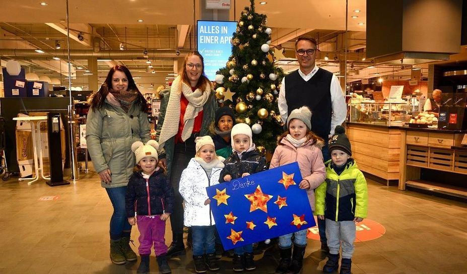 Famila-Marktmanager Hajo Golsch freute sich über den Besuch von Kita-Leitung Maylin Wilczynski (Mitte), Erzieherin Nele Röver und den Kita-Kindern, die ein Bild überreichten.
