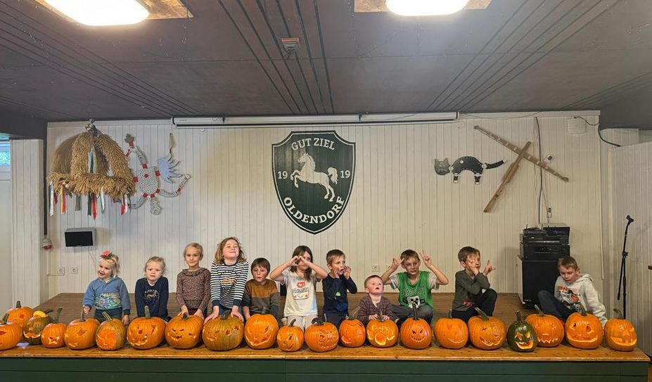 Die Kinder präsentieren stolz die Ergebnisse ihrer Kürbissschnitzkunst.