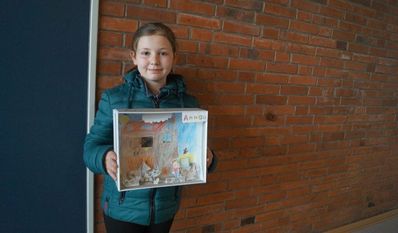 Raphael neben seinem Bild zum Thema, was Kinder tun, wenn der erste Schnee fällt. Zweitklässlerin Anna hat im Unterricht ein Bauernhof-Diorama gebastelt.