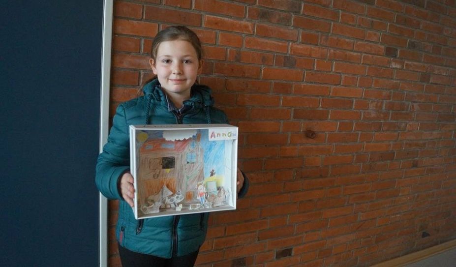 Raphael neben seinem Bild zum Thema, was Kinder tun, wenn der erste Schnee fällt. Zweitklässlerin Anna hat im Unterricht ein Bauernhof-Diorama gebastelt.