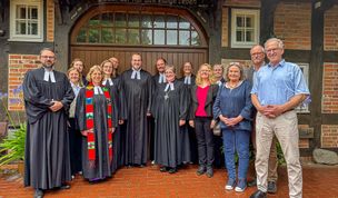 Pastoren und Pastorinnen, Diakoninnen, Assistenten und die Regionalbischöfin nehmen ihren neuen Kollegen Pastor Jakob Schiffer in die Mitte.