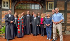 Pastoren und Pastorinnen, Diakoninnen, Assistenten und die Regionalbischöfin nehmen ihren neuen Kollegen Pastor Jakob Schiffer in die Mitte.