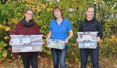 Elke Wladarsch (Schulleiterin, l.) und Sanja Winkelmann (Fachleitung Sachunterricht, r.) freuen sich über die neuen Materialkisten, die Bettina Schroeder (NABU) der Grundschule Engeo für das neue Projekt „Umweltbildung querbeet“ überreicht.