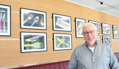Ulrich Reiß vor seinen farbenfrohen Fotografien in der Cafeteria des Landkreises Osterholz.