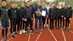Jan Petermann mit Blumen und Urkunde im Kreise seiner Leichtathleten.