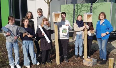 Die Kinder der Garten- und Nachhaltigkeits-AG nehmen freudig die Forscher-Nisthilfen von der NABU Umweltpyramide entgegen.