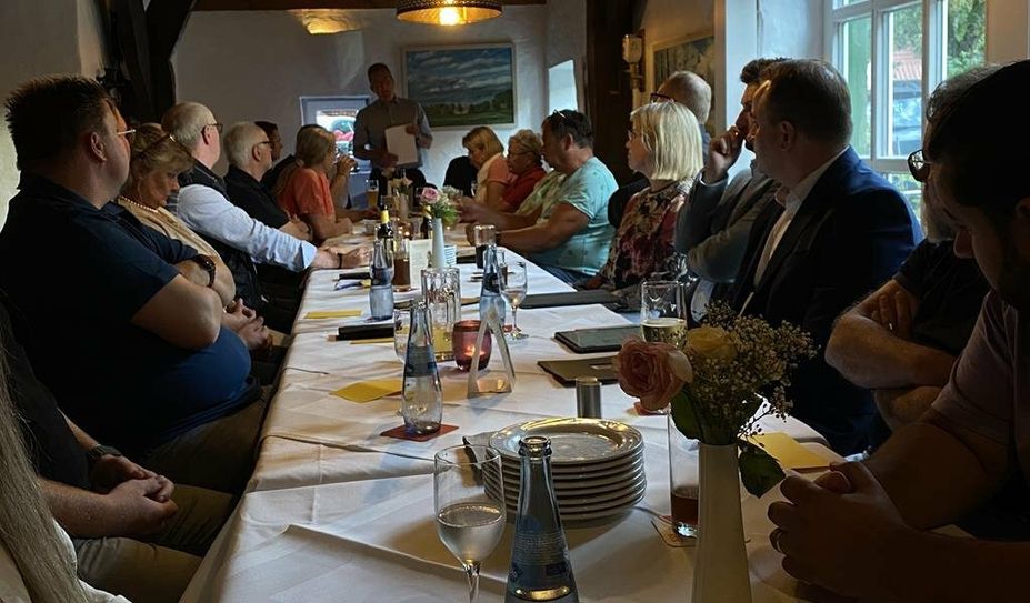 21 stimmberechtigte Mitglieder sitzen zusammen am Tisch bei der Jahreshauptversammlung des Schwaneweder Gewerbevereins.