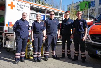Sanitäterinnen und Sanitäter der DRK-Bereitschaft vor ihren Einsatzfahrzeugen.
