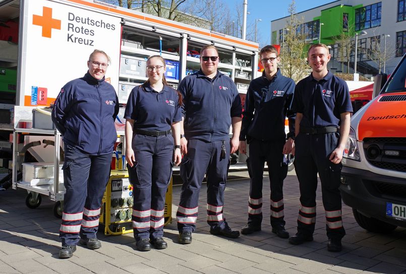 Sanitäterinnen und Sanitäter der DRK-Bereitschaft vor ihren Einsatzfahrzeugen.