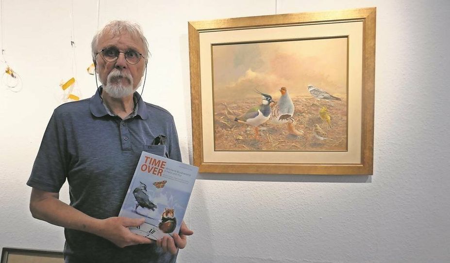 Maler Bernd Pöppelmann mit seinem Gemälde von bedrohten Vogelarten.