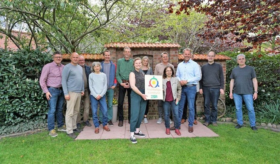 Luisa Wolter von der Kommunalen Umwelt-AktioN (vorne li.) überreichte das Nachhaltigkeitslabel an Bürgermeister Guido Dieckmann (3. v. re.) und Mitglieder der Arbeitsgruppe.