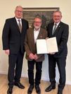 Landrat Bernd Lütjen und Axel Miesner (CDU ) überreichten Manfred Sievers seine Ehrung im Dorfgemeinschaftshaus Adolphsdorf.