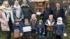 Die Kinder und Fachkräfte vom „Abenteuerland“ versammeln sich vor der neuen Wildbienen-Nisthilfe und freuen sich über den Leitfaden und das Schild für die Kita.