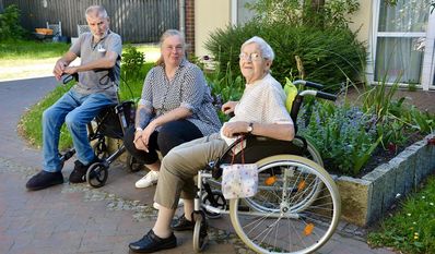 Sandra Idem zeigt mit Bewohner:innen einen Teil der schönen Außenanlagen
