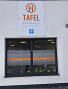 Neues Schild und Fensterbeklebungen machen die Osterholzer Tafel in der Kirchenstraße auch von außen deutlich erkennbar.