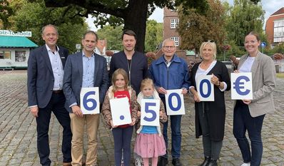Freuen sich über die Gewinnübergabe: Die Sieger:innen sowie die Volksbankmitarbeitenden Jan Mackenberg (links) und Pia-Sophie Meyer (rechts).