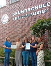 Bettina Schroeder (links) überreichte die Urkunde und die Palette an das Kollegium.